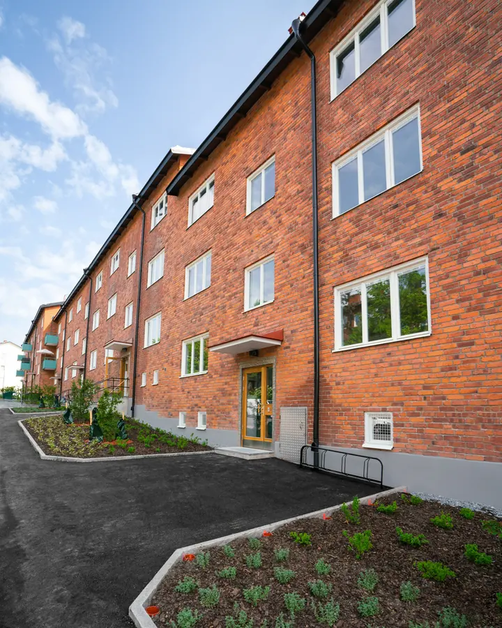 Flerbostadshus i rött tegel med gräsmatta