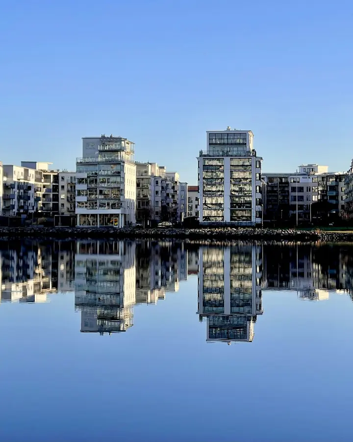 Moderna flerbostadshus vid vattnet som speglar sig i ytan