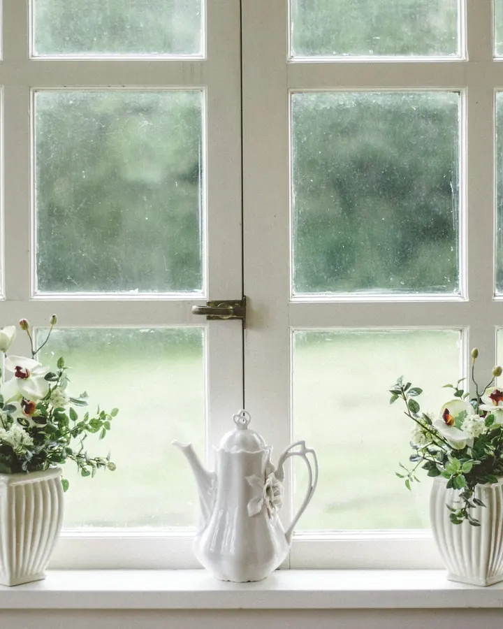 Spröjsat fönster med vita bågar och blommor på fönsterbänken